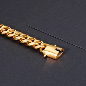 Macro detail of gold-plated Cuban chain bracelet with secure lobster clasp and metal texture