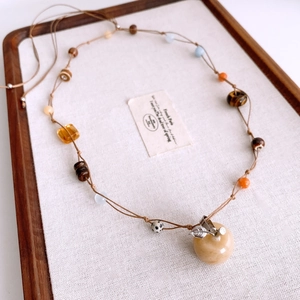 Detail of beaded tiger eye necklace featuring an apple-shaped pendant and mixed beads