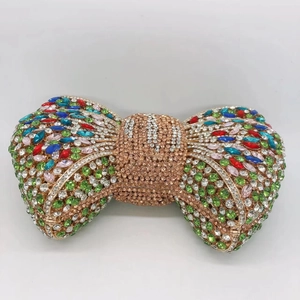 Detailed view of rose gold bow clutch bag encrusted with colorful sparkling rhinestones