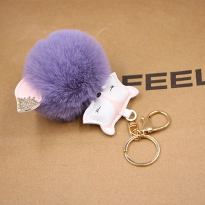 Detail of purple faux fur ball fox keychain with pink leather head and gold lobster clasp