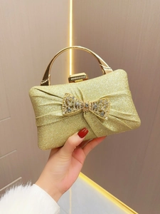 Detailed macro of gold sequin evening clutch bag with large rhinestone-studded bow