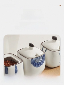 Detail of ceramic spice jars with notched lids and wooden tray for easy spoon storage
