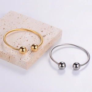 Macro detail of gold and silver twisted cable bangles with metal spheres on stone