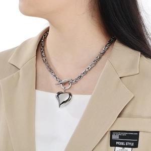 Close-up of a silver Byzantine chain necklace with a heart pendant and toggle clasp on model