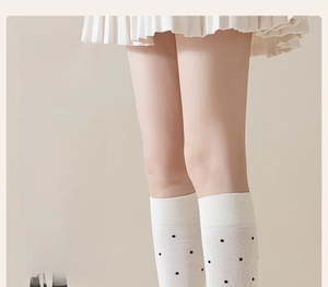 Detailed view of calf-high cotton socks with vintage polka dots on standing legs