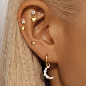 Macro shot of gold opal moon and star cartilage piercings on ear showing zircon details