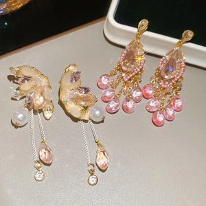 Detailed macro view of luxurious silver pin earrings with crystal butterfly and pearl tassels