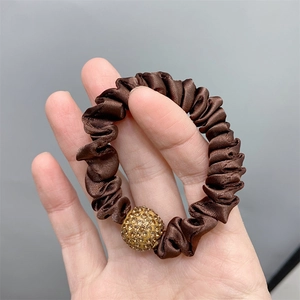 Detail of brown silk scrunchie with a gold rhinestone ball decoration for women