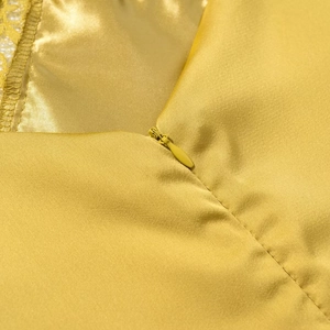 Detail of the high-quality invisible zipper on yellow satin silk midi dress fabric