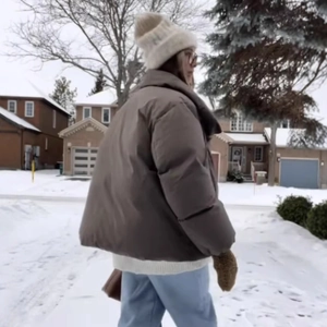 Outdoor shot of a brown puffer jacket with white knit hat and matching brown gloves