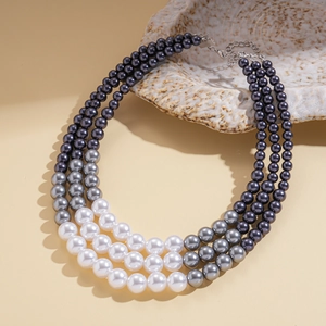 Detail view of a three-layer gradient faux pearl necklace with adjustable silver clasp