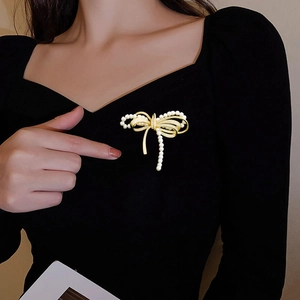 Close-up of golden bow brooch with pearls and zircon crystals worn on black fabric