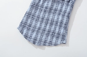 Detailed view of the blue and white smocked textured fabric on a stylish plaid outfit