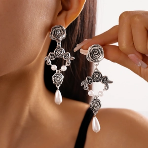 Close-up of vintage rose flower earrings with teardrop pearls and antique silver finish
