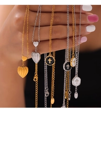Detail of gold and silver necklaces featuring heart and cross pendants held by hand
