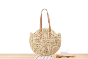 Detailed view of the spiral hand-woven pattern and leather handle on the round straw bag