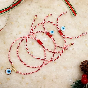 Close-up of four handmade evil eye woven bracelets with red string and gold beads
