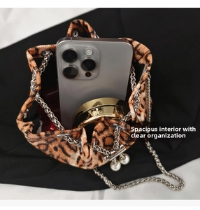 Detail of leopard print crossbody bag showing spacious interior with phone and lipstick