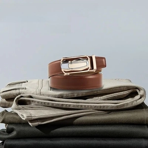 Close-up of brown leather belt with two-tone automatic buckle on folded trousers