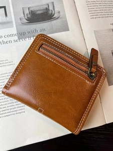 Detail of brown leather coin purse with white stitching on a magazine background
