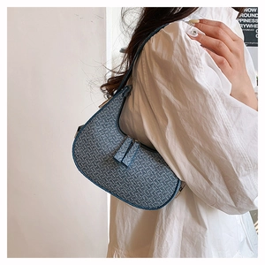 Close-up of blue woven texture crescent shoulder bag with metallic buckle detail