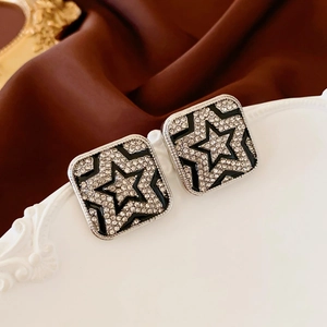 Detailed close-up of square star earrings with black enamel and sparkling rhinestones
