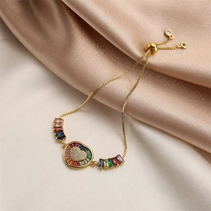 Close-up of heart charm with rainbow zircon inlays on golden adjustable chain