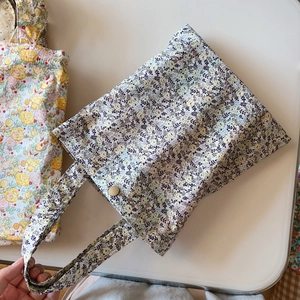 Detail showing floral cotton tote bag with metal snap button and dual carry handles