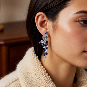 Detail of blue and purple butterfly tassel earrings with teardrop crystals on a model