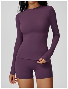 Detail shot of slim-fit dark purple yoga set with long sleeve top and high-waist shorts