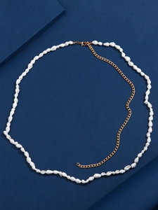 Detail of bohemian gold waist chain with natural white shells on a navy textured background