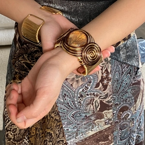 Detail of bohemian gold wire-wrapped bracelet featuring a faceted amber crystal gemstone