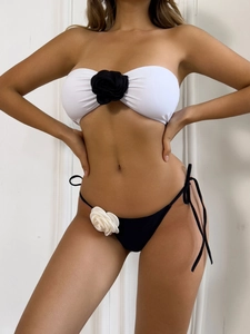 Close-up of white bandeau bikini top with a 3D black flower and black side-tie bottoms