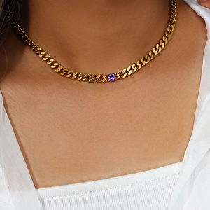 Macro view of a 6.5mm gold Cuban chain necklace featuring a round purple gemstone