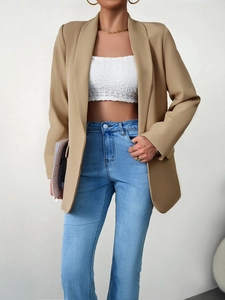 Détail du blazer kaki porté avec un bustier blanc et un jean bleu style bureau