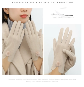 Detail of beige faux suede gloves with plush fur pom-poms on the elastic cuffs