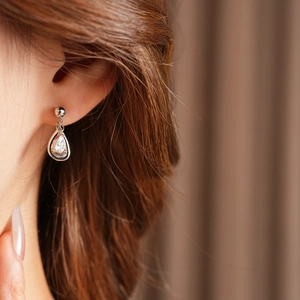 Close-up of model wearing sparkling teardrop zircon earrings with silver needle posts