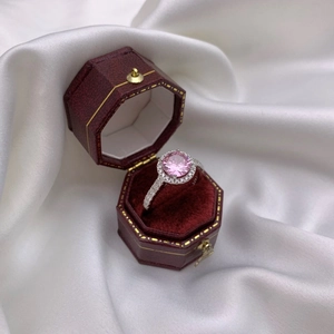 Pink round-cut diamond ring presented in a vintage red velvet jewelry box with silk backdrop