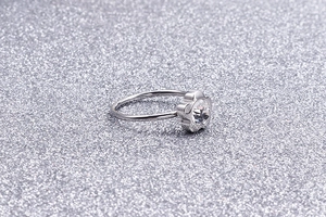 Macro shot of minimalist flower-shaped zircon ring with polished silver finish