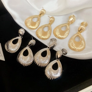 Detailed view of teardrop earrings with fan-shaped textures in gold and silver finish