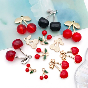Flat lay of red and black cherry charms for DIY jewelry making in glossy finish