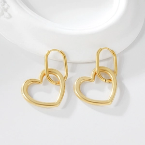 Minimalist golden hollow heart drop earrings with oval hoops on white marble tray