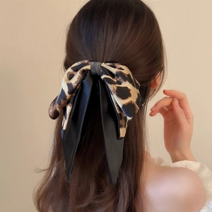 Leopard print bow hair clip with rhinestones shown on model in a stylish hair arrangement