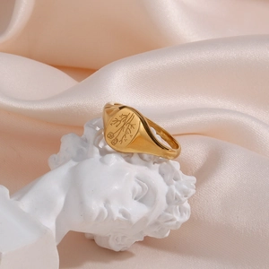 Vintage golden signet ring with engraved flower pattern on white sculpture