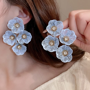 Gros plan de boucles d'oreilles fleurs bleues élégantes portées par un mannequin
