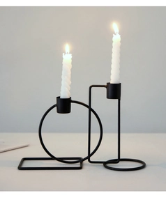 Detail of minimalist black geometric metal candle holder with lit white spiral candles