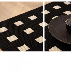 Close-up of modern geometric woven door mat with black and white grid patterns