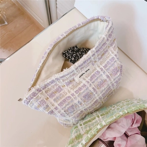 Close-up of purple tweed cosmetic bag with gold threads and interior floral accessory