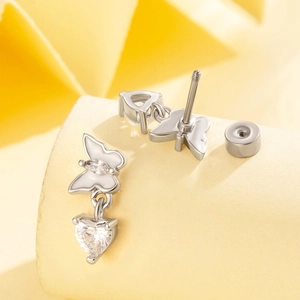 Silver butterfly and heart pendant ear piercings with screw back on a yellow stand