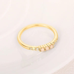 Makro-Detail des goldenen Minimalist-Rings mit drei rosa Opalen und weißen Zirkonia